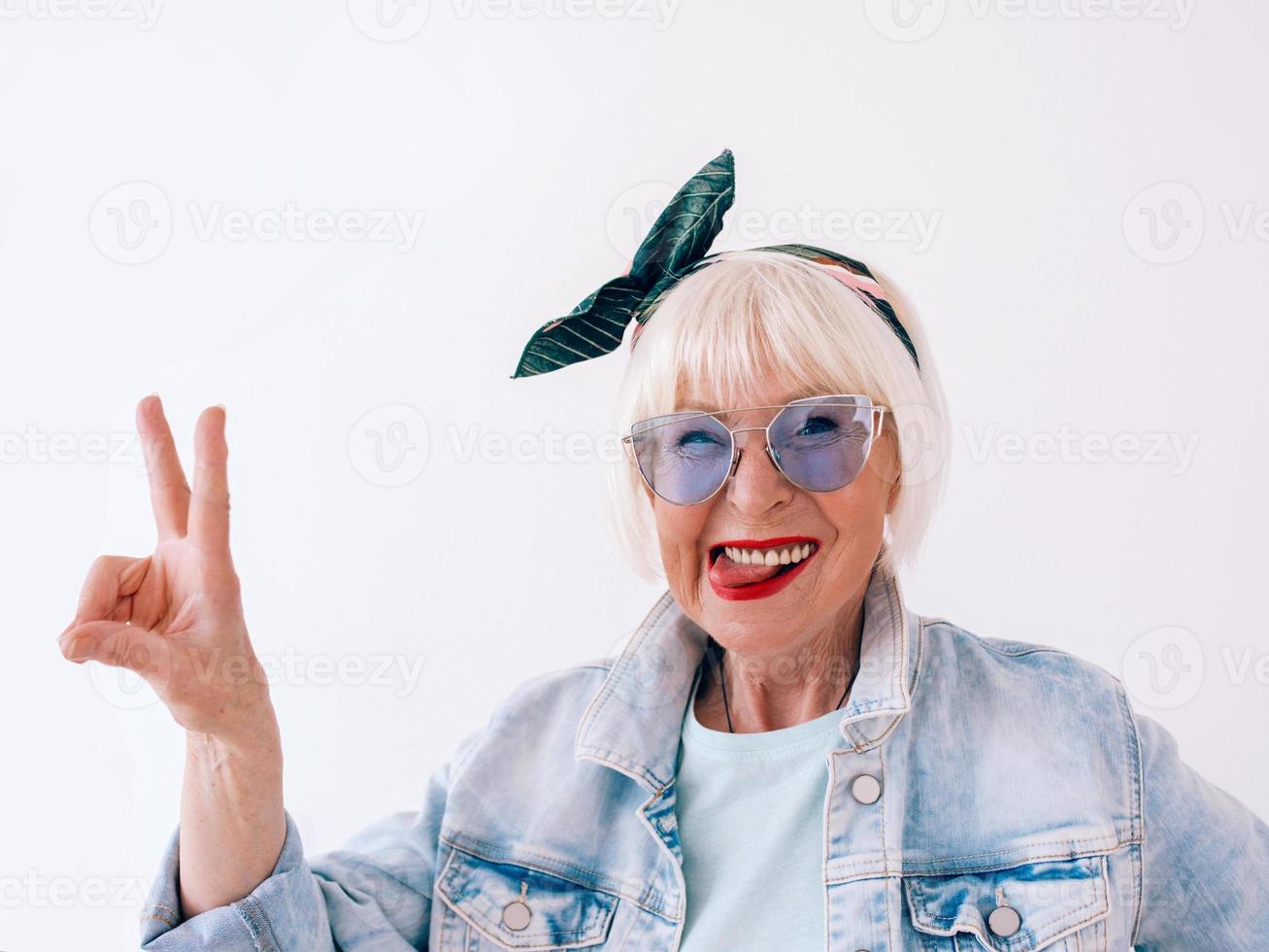 mulher elegante sênior, com cabelos grisalhos, com uma bandana na moda e óculos azuis. moda, anti-idade, relaxamento, feriados, conceito de aposentadoria foto