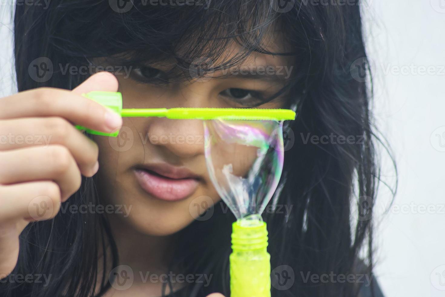 uma garota segurando um fabricante de bolhas e soprando-os para fora. foto