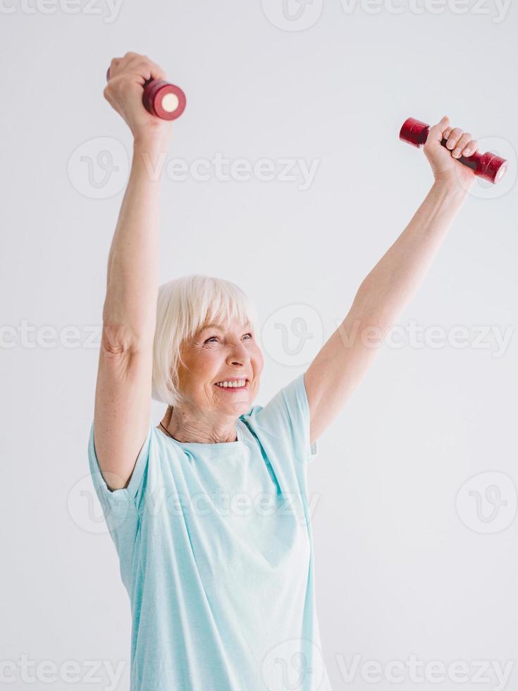 mulher alegre sênior fazendo esportes com halteres. conceito de estilo de vida saudável, anti-idade, esportes foto