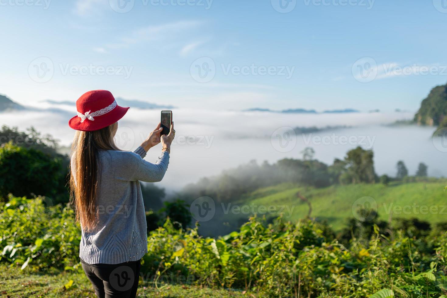 mulher viajante usando chapéu usando telefone inteligente, pegue uma bela montanha foto