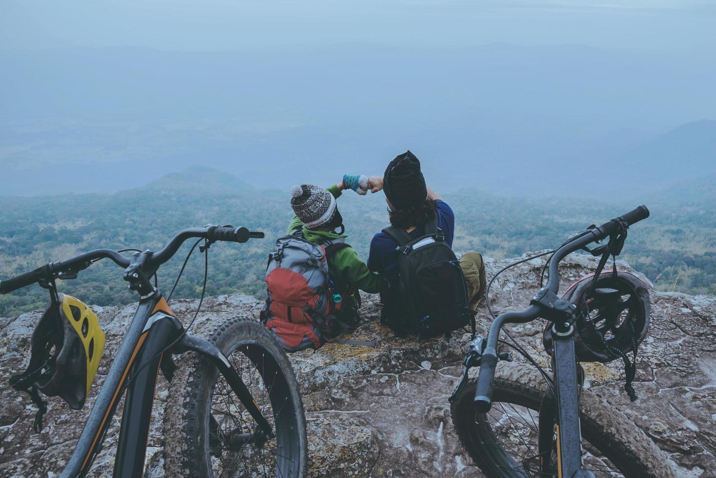 Amantes asiáticos mulheres e homens viajam pela natureza. viajar relaxar andar de bicicleta de montanha em estado selvagem. sente-se em um penhasco rochoso. Tailândia foto