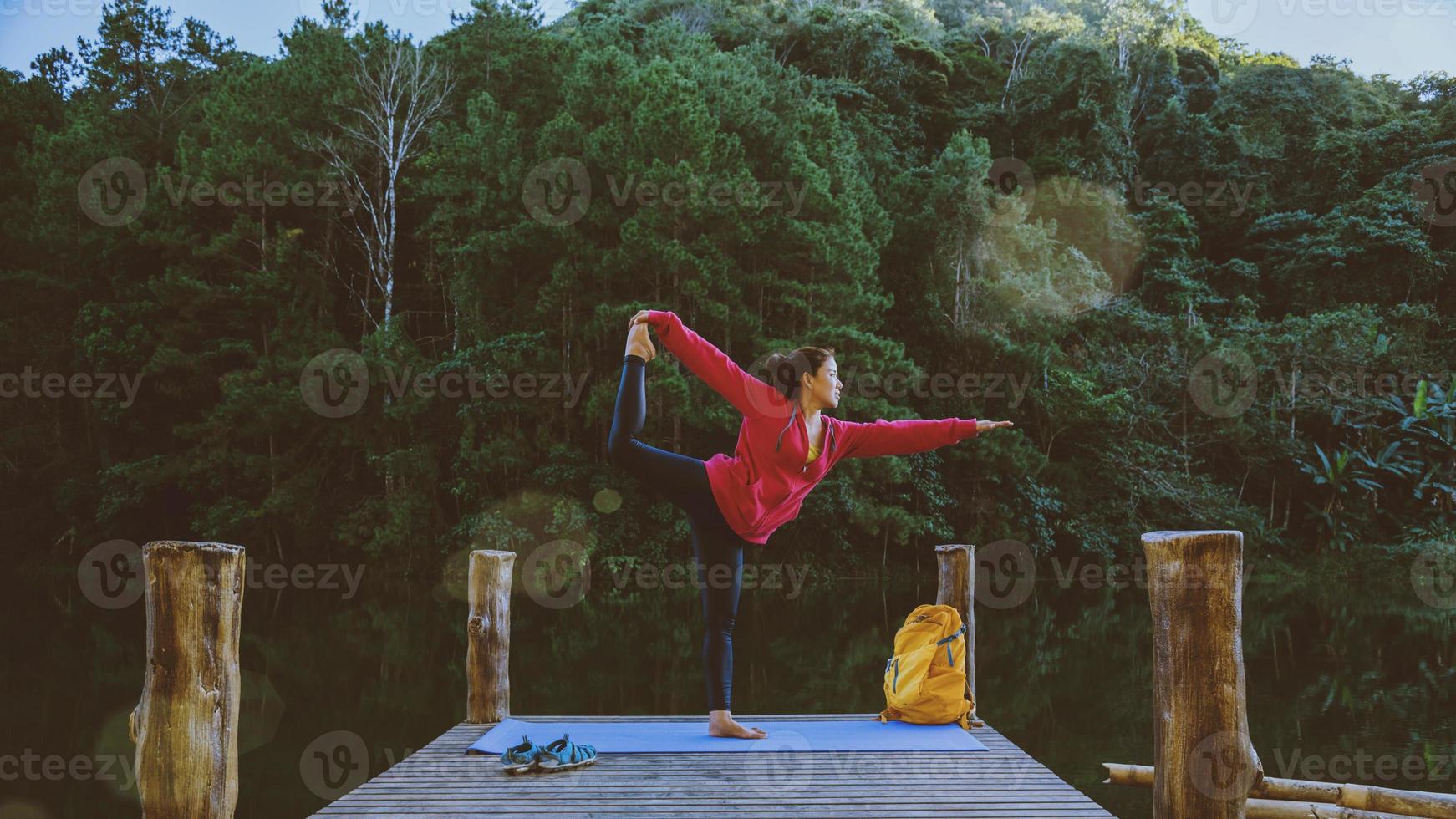 mulheres asiáticas relaxam no feriado. jogar se ioga. na montanha, exercite-se, pratique ioga na ponte de bambu ao lado do lago na névoa em pang ung, tailândia. foto