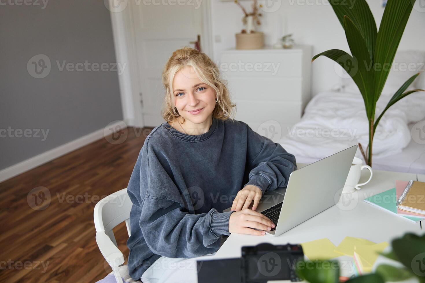 retrato do jovem loiro mulher com computador portátil, gravação em digital Câmera, criada blog, vlogging dentro dela sala, edição em computador foto