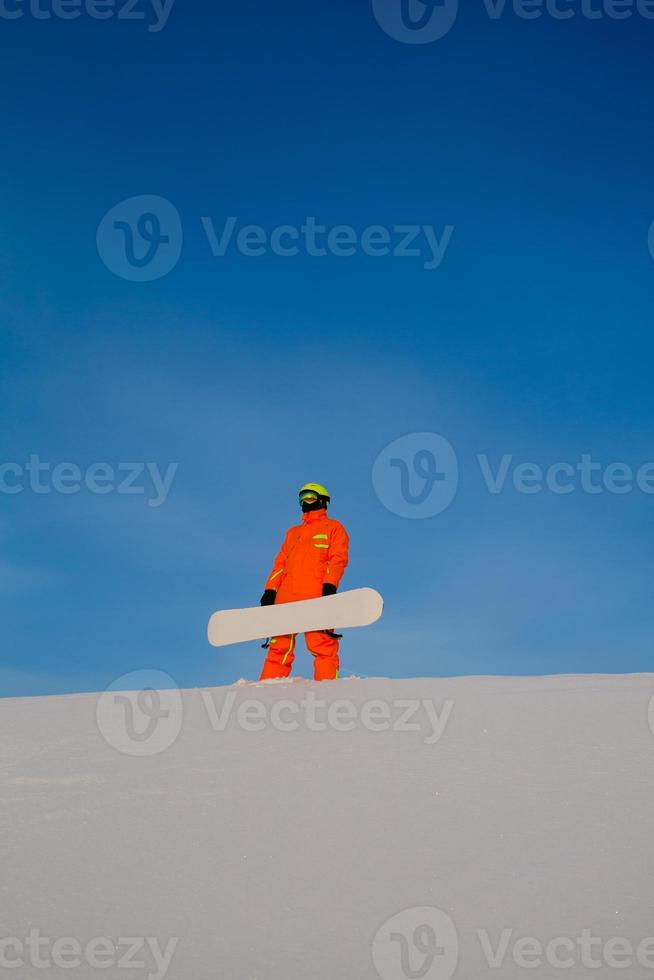 snowboarder freerider com snowboard branco sentado no topo da pista de esqui foto