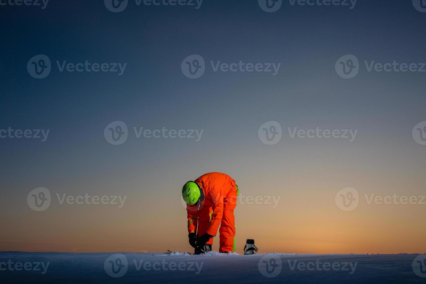 snowboarder no topo de uma pista de esqui ao fundo de um belo pôr do sol foto