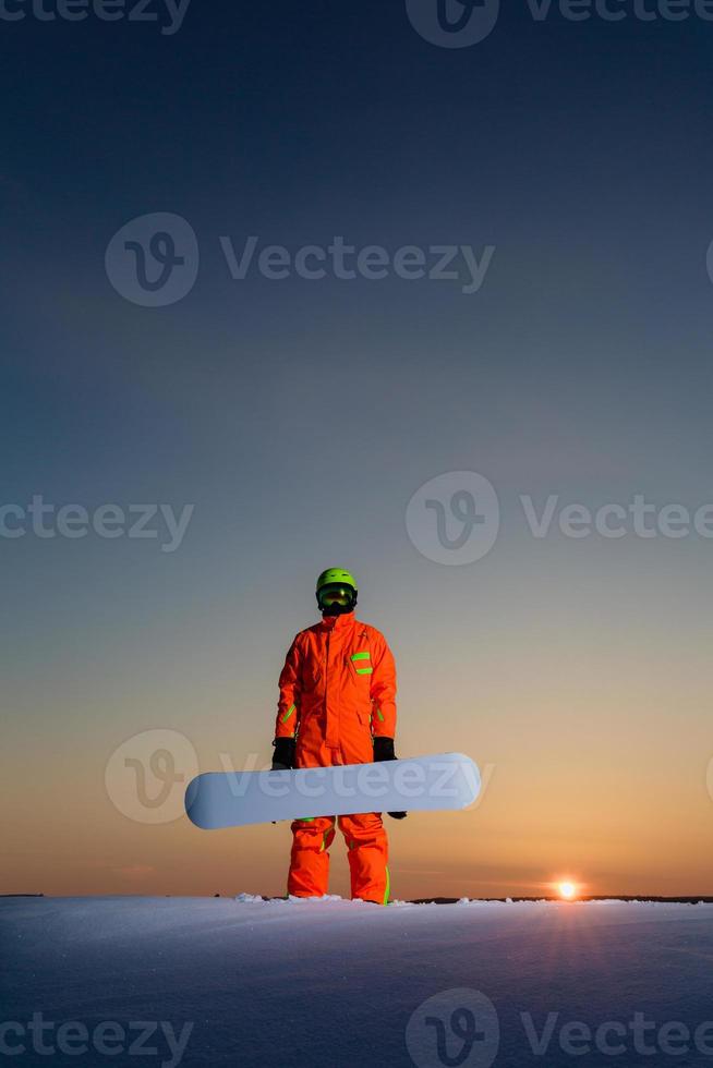 snowboarder no topo de uma pista de esqui ao fundo de um belo pôr do sol foto