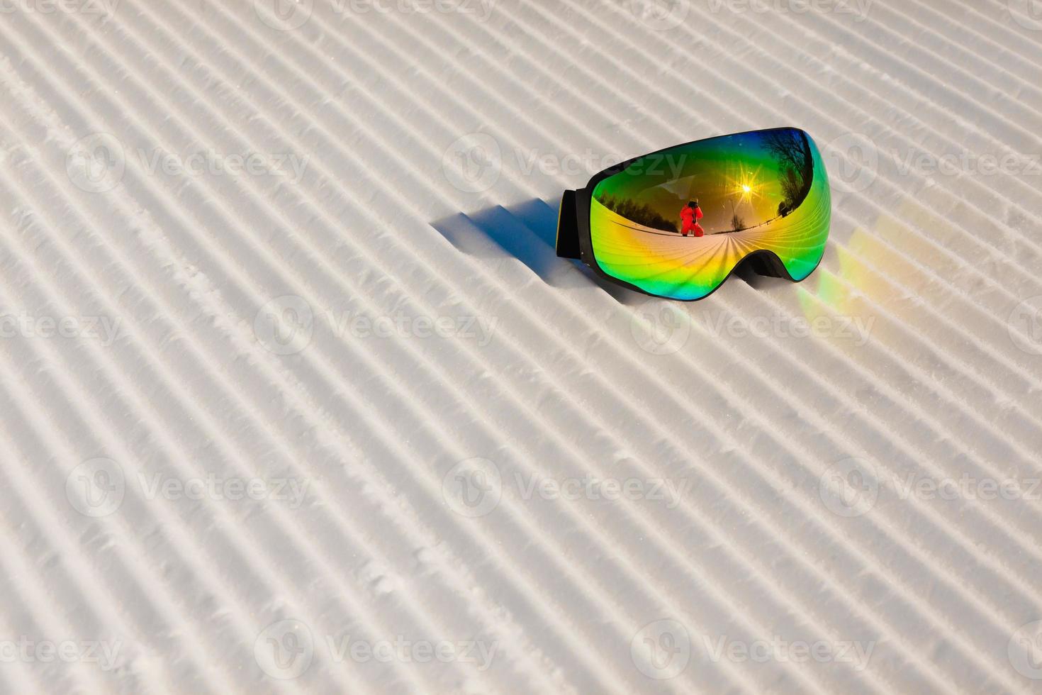 óculos de esqui em uma neve limpa e em uma pista de esqui vazia foto