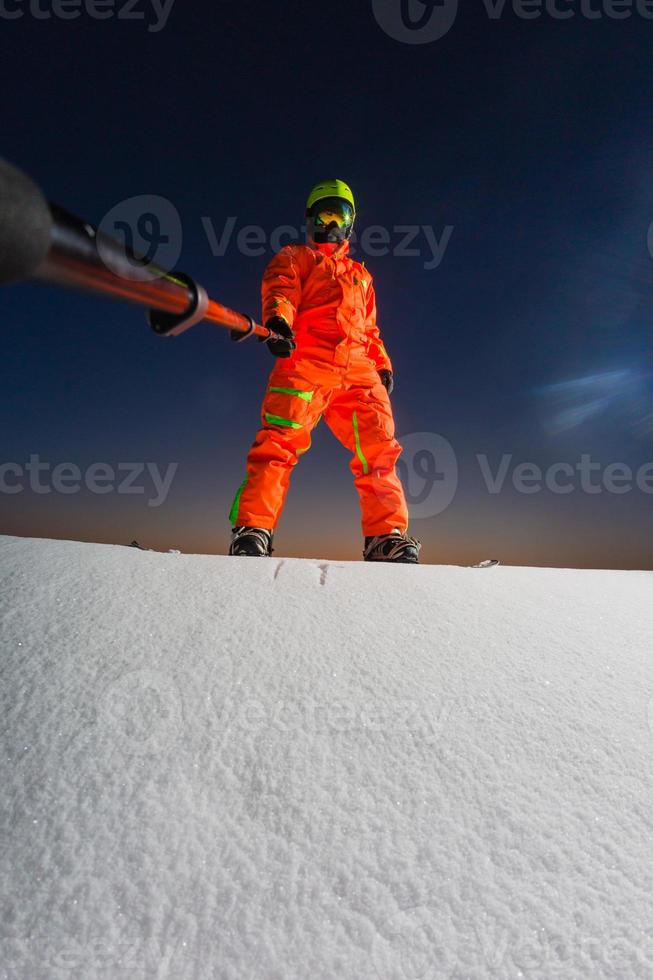 snowboarder fazendo uma selfie com sua câmera de ação no topo de uma pista de esqui foto