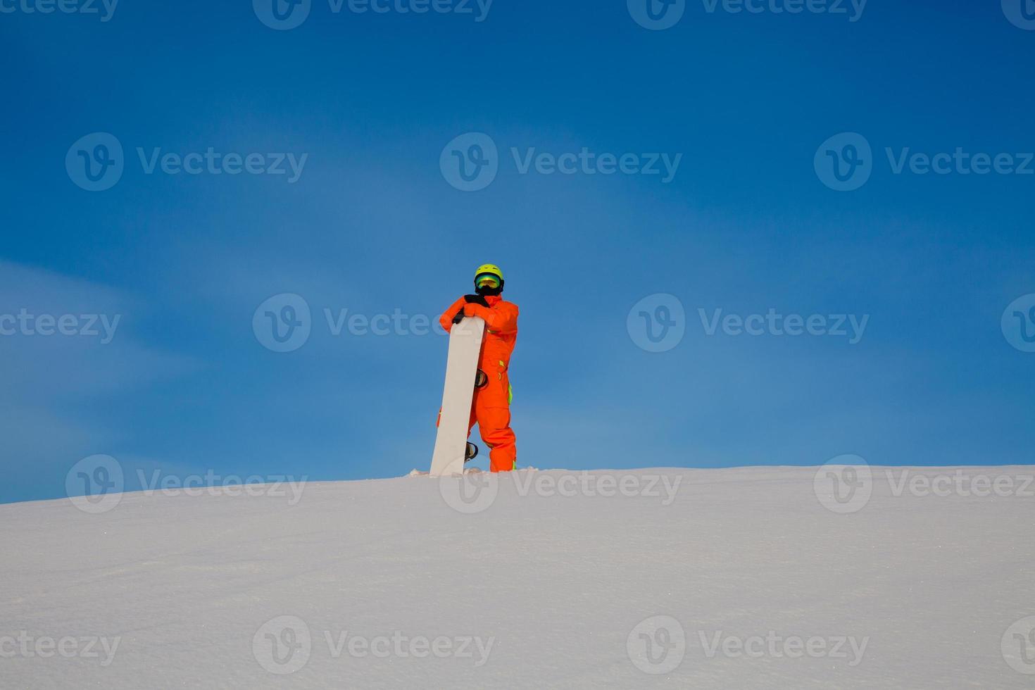 snowboarder freerider com snowboard branco em pé no topo da pista de esqui foto
