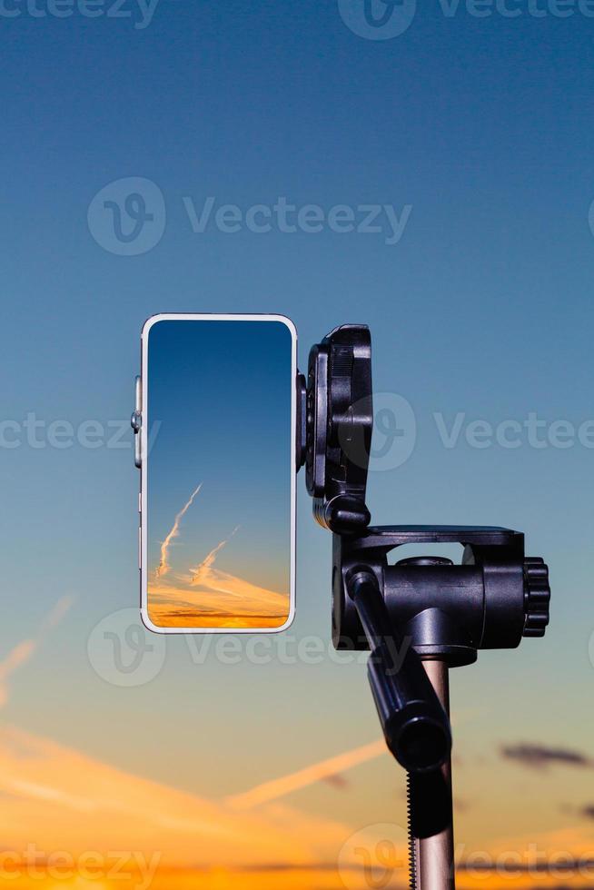 smartphone no tripé capturando imagem do pôr do sol no modo vertical foto