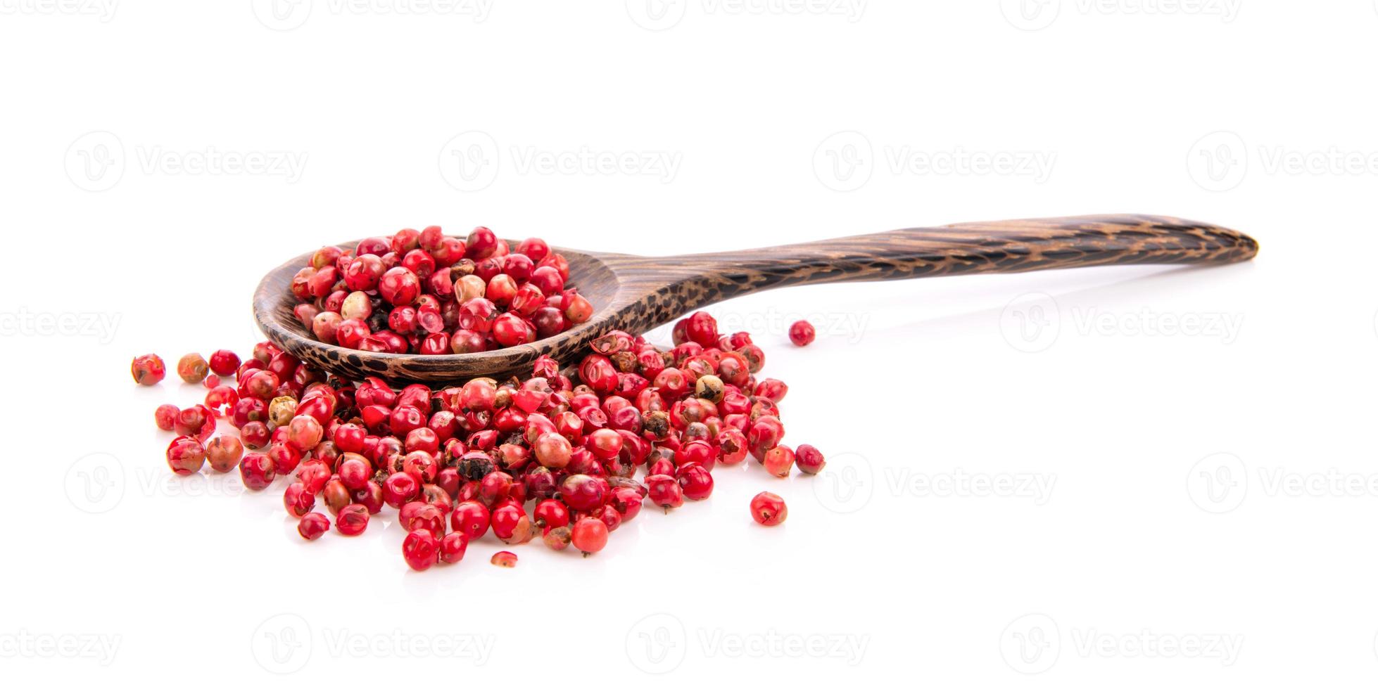 pimentas rosa secas em colher de madeira isoladas no fundo branco foto