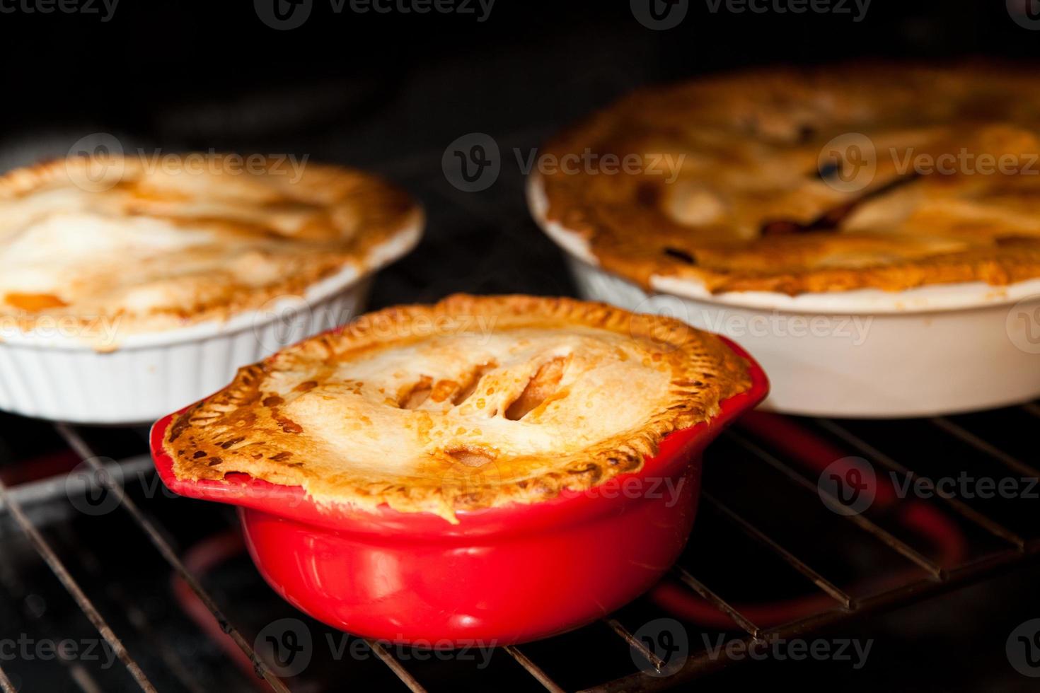 três tortas de maçã cozinhando no forno foto