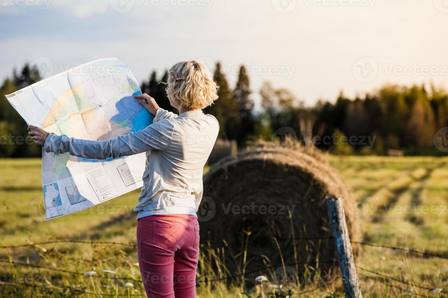 mulher perdida em uma cena rural olhando para um mapa foto