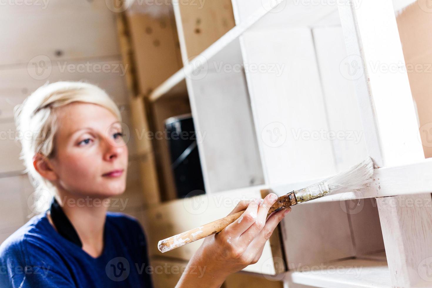 mulher aplicando a primeira camada de tinta em uma biblioteca de madeira foto
