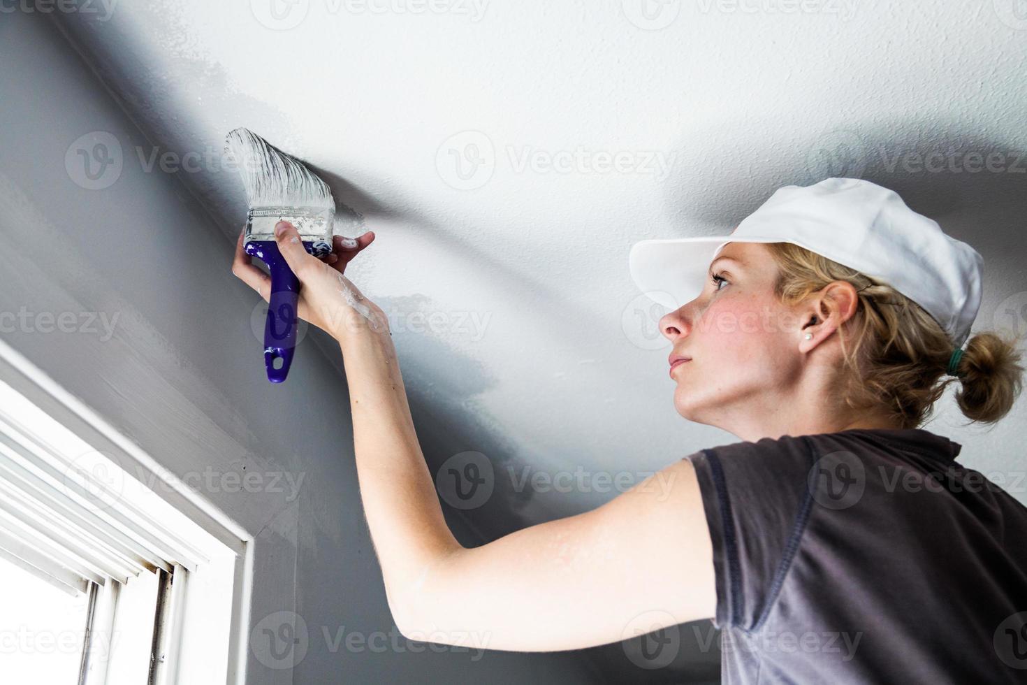 mulher pintando as bordas do teto foto