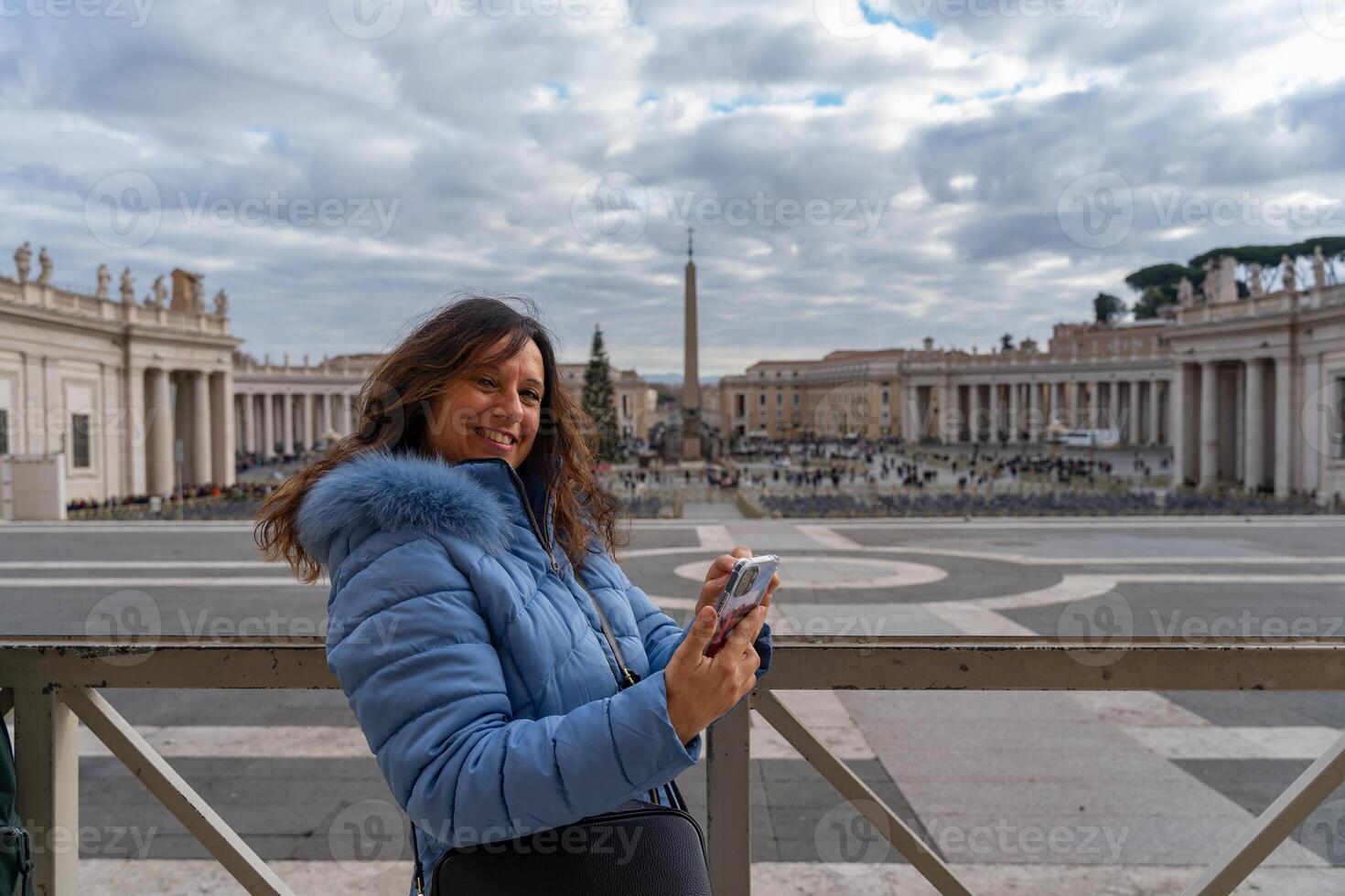 feliz meio envelhecido fêmea turista usando Móvel telefone dentro frente do san pietro quadrado dentro Roma foto