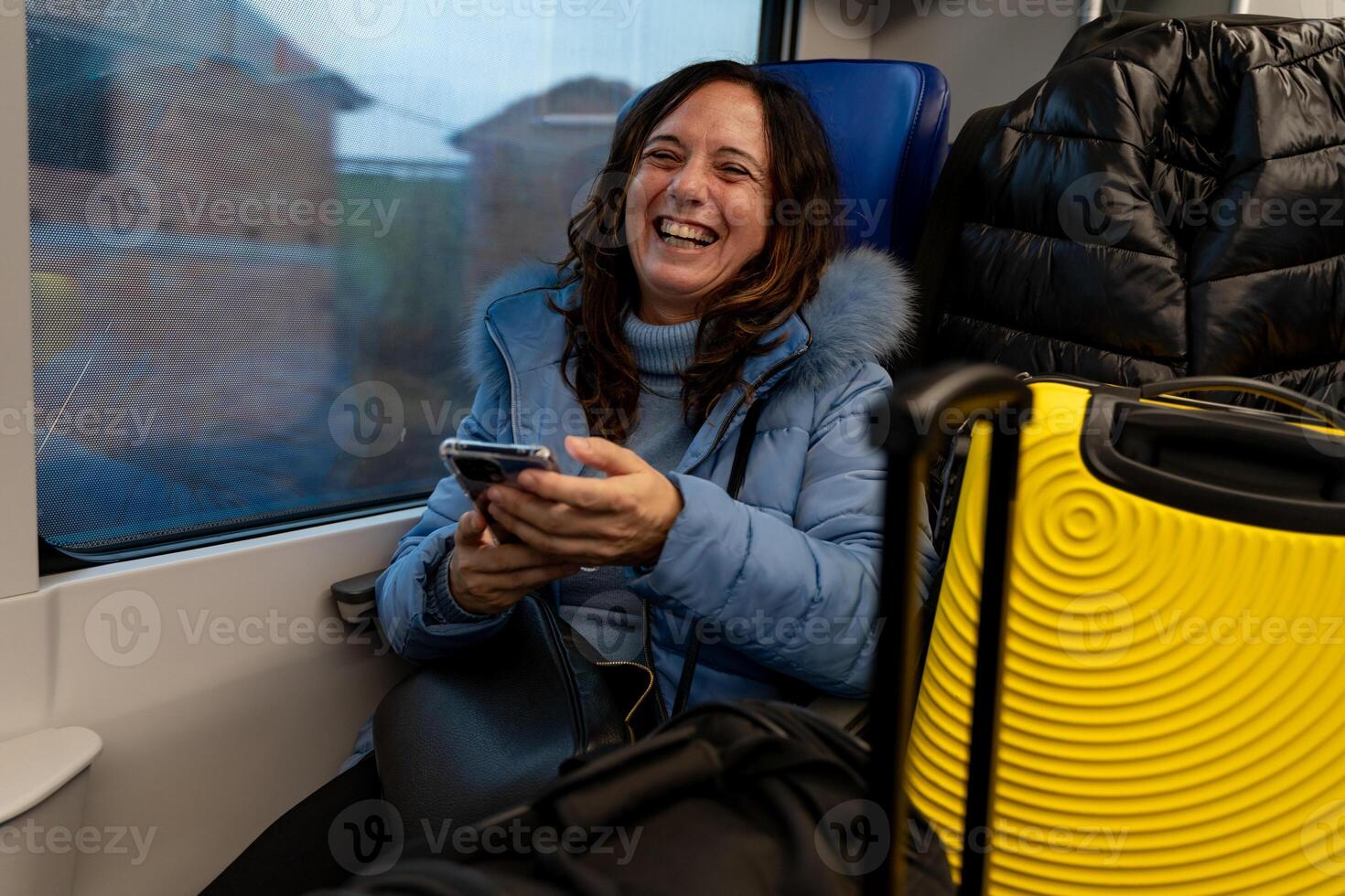 bonita meia idade mulher viajando em a trem sentado entre a bagagem Próximo para a janela usando a inteligente telefone foto