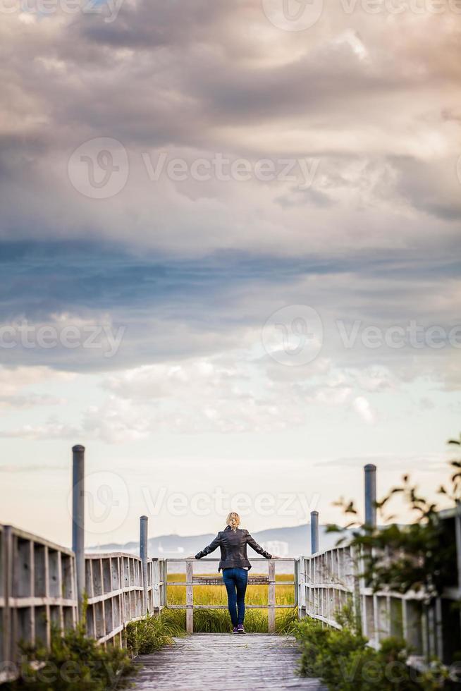 jovem solitária olhando para a incrível paisagem calma de uma varanda de madeira foto