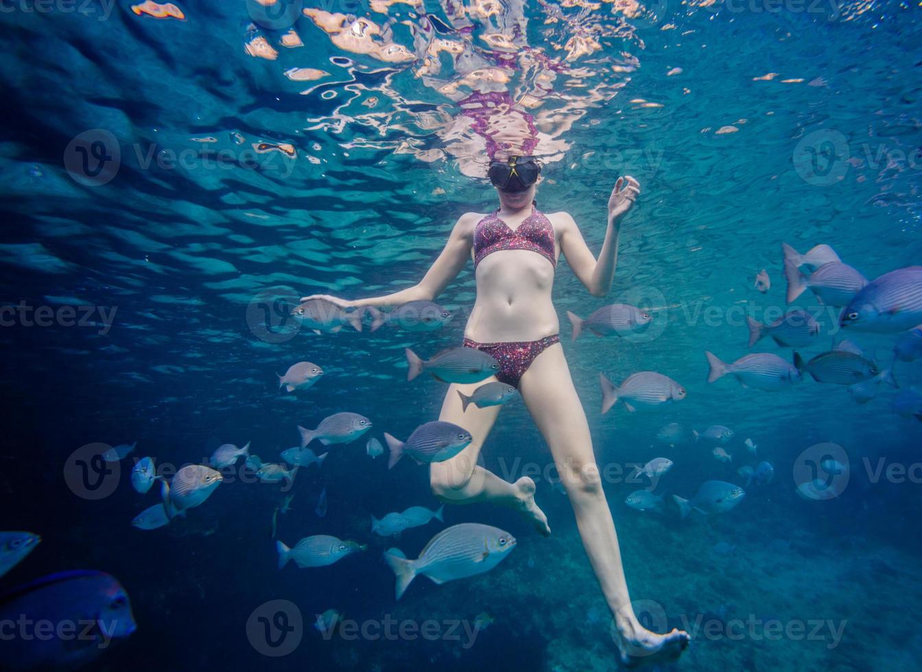 menina fazendo snorkel e cercada por peixes chopa foto