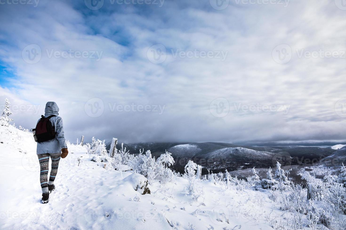 mulher caminhando no alto das montanhas durante o inverno foto