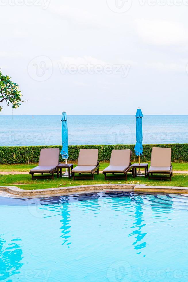 cadeira de piscina com guarda-sol ao redor da piscina foto