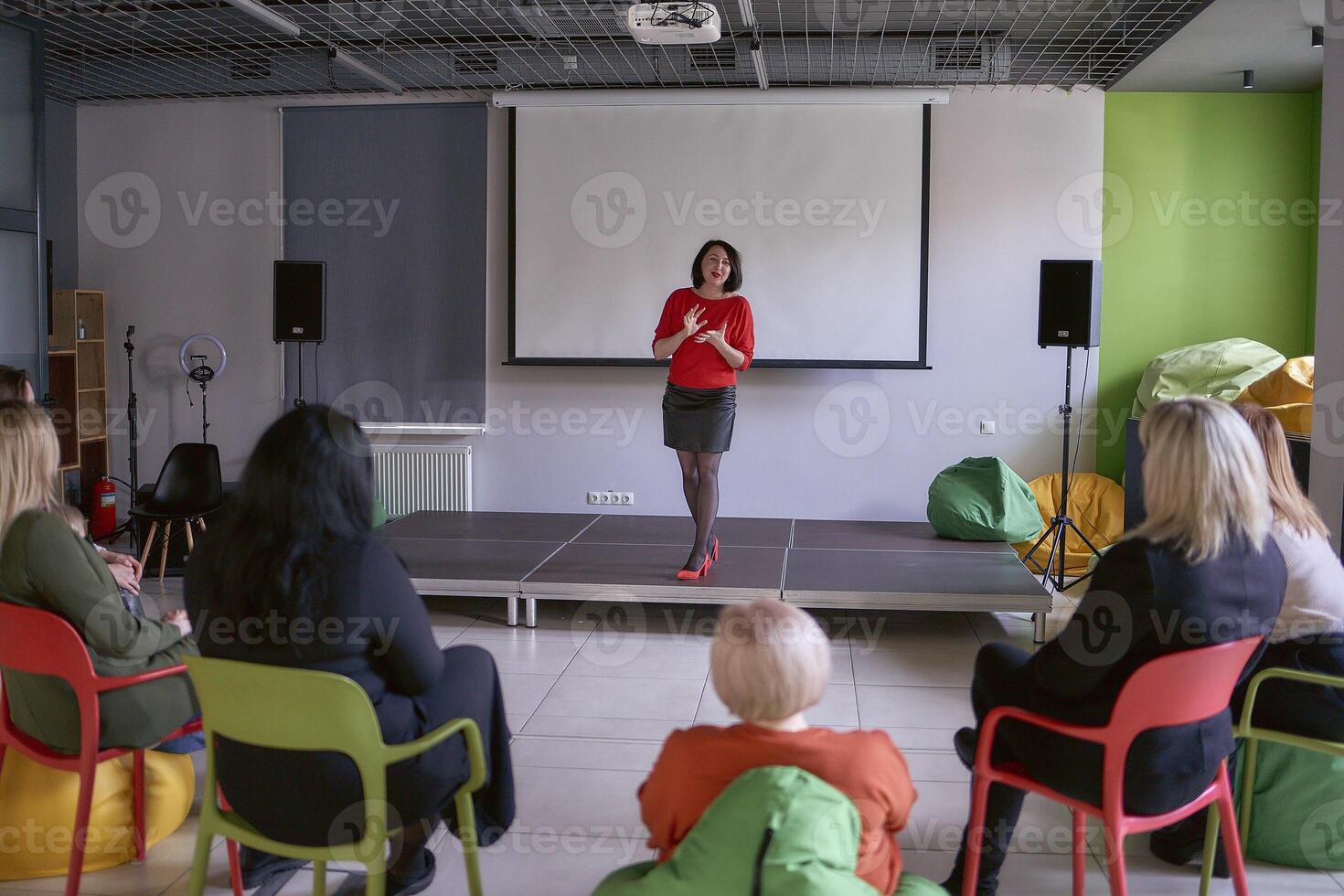 mulher dando emocional discurso em estágio, desempenho corredor dentro escritório foto