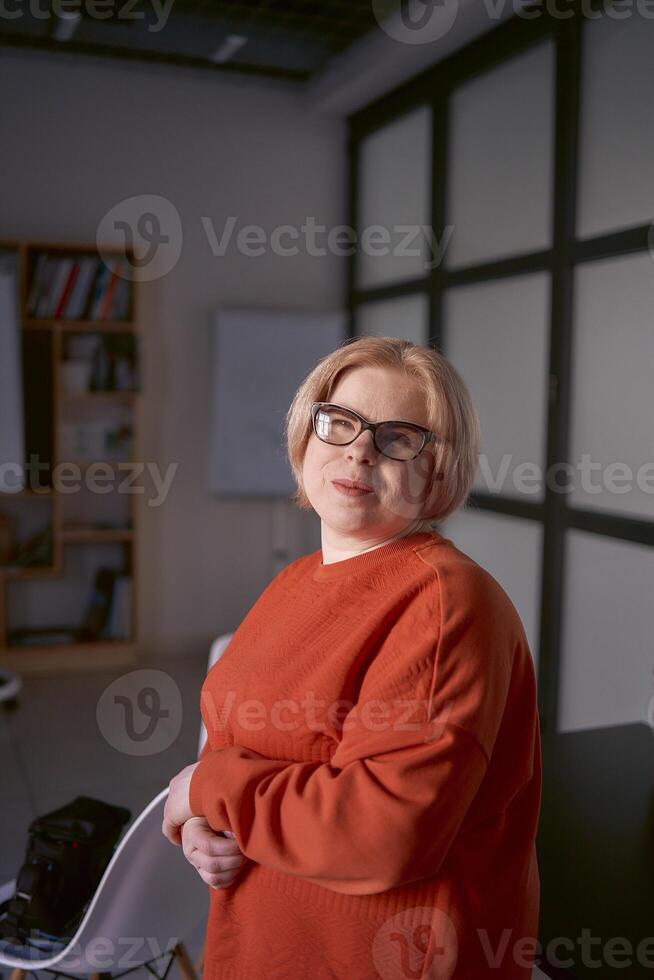 retrato do uma mulher com uma incapacidade dentro a laranja suéter e couro calça dentro a escritório foto