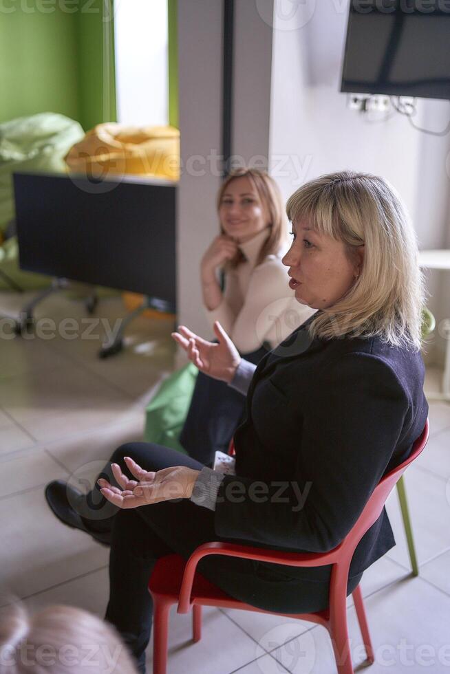 mulheres Assistir seus do colega discurso em estágio, sentado em cadeiras e feijão saco foto