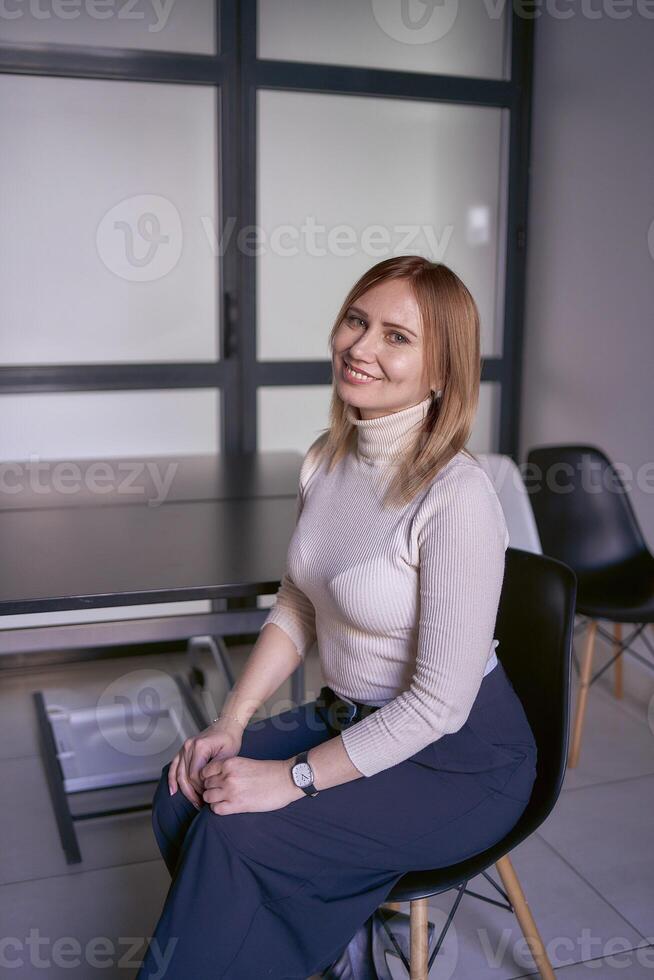 Loiras mulher dentro uma luz suéter e Largo calça dentro a escritório foto