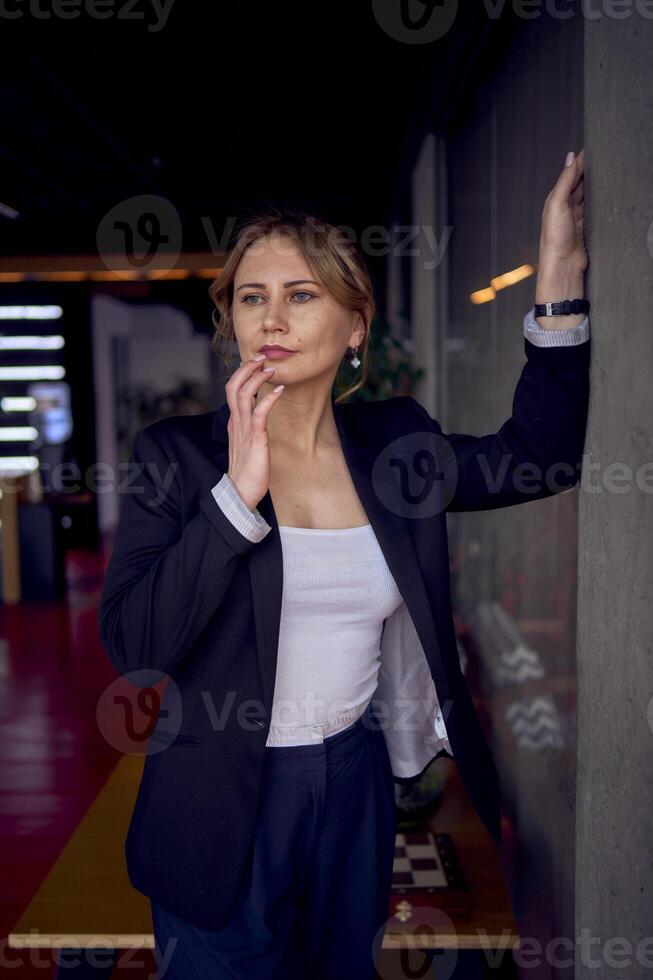 atraente meio era mulher dentro Jaqueta e branco camiseta posando dentro Barra com moderno Projeto foto