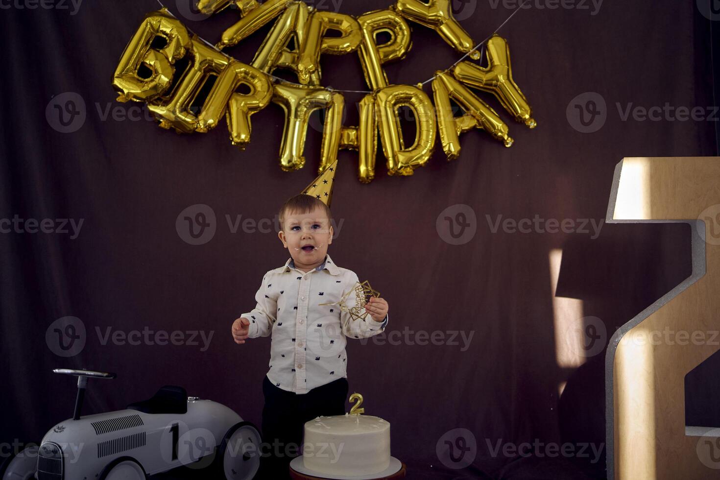 uma criança pequena é feliz com uma aniversário bolo e apresenta em dele segundo aniversário foto