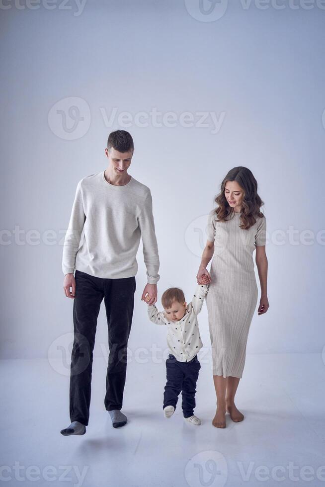 uma minimalista retrato do uma mãe, pai e seus criança de dois anos filho em uma branco fundo foto