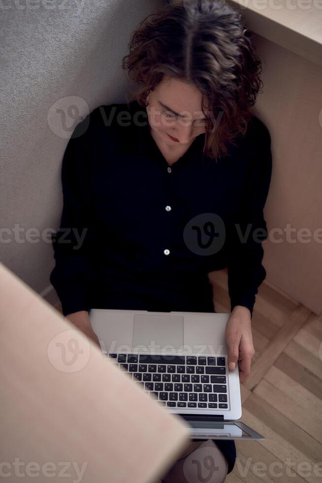 mulher trabalhos com computador portátil em a chão foto