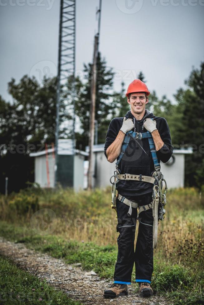 homem técnico de telecomunicações de uniforme com arnês foto