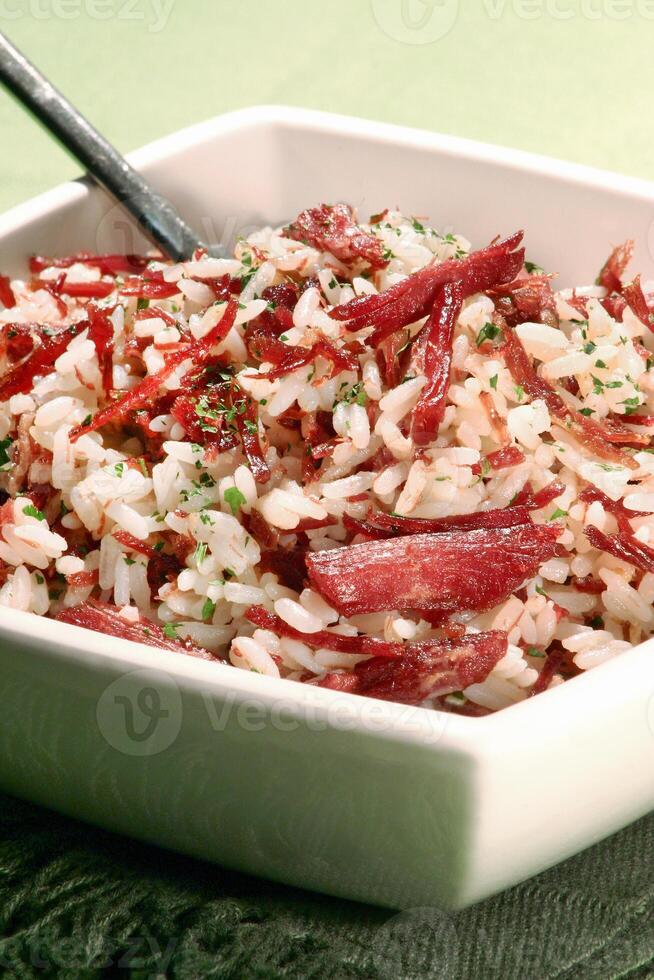 arroz de carreteiro, uma clássico brasileiro prato com arroz, seco carne, fatiado bacon, cebola e salsinha foto