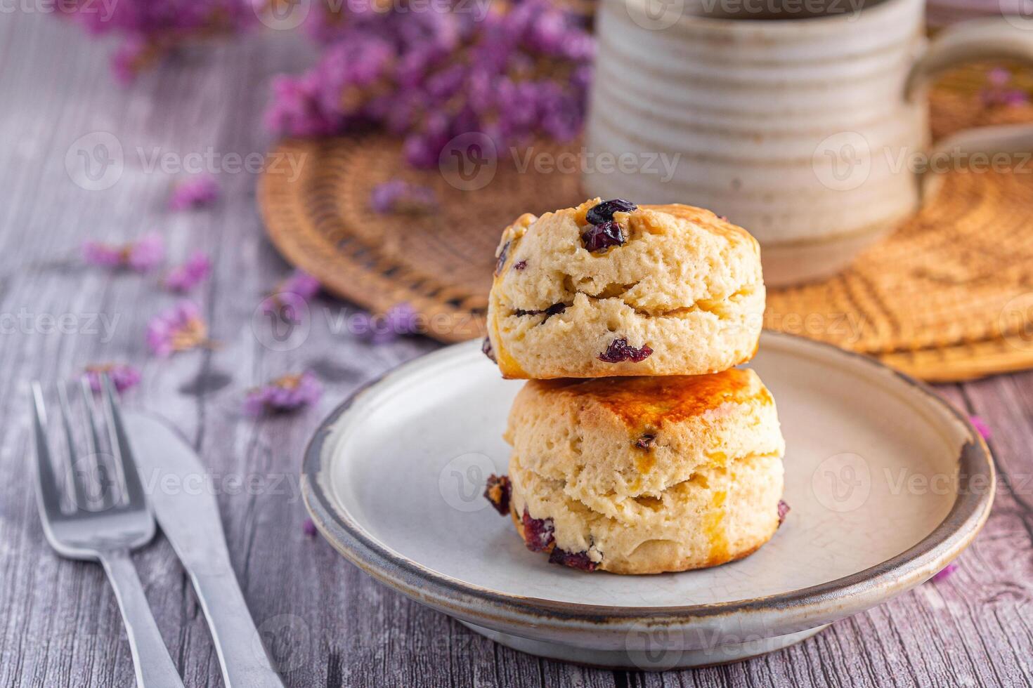 fechar-se do tradicional britânico scones em uma prato com uma chá copo e flor borrado fundo foto