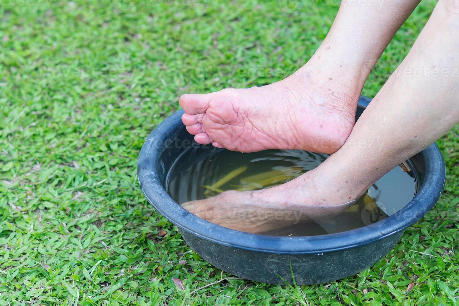 fechar-se do spa pé com ervas água para relaxamento tratamento. uma Senior mulher com tornozelo dor usa ervas tratamento para relaxar a músculos de encharcado caloroso água este é fervido a partir de ervas foto