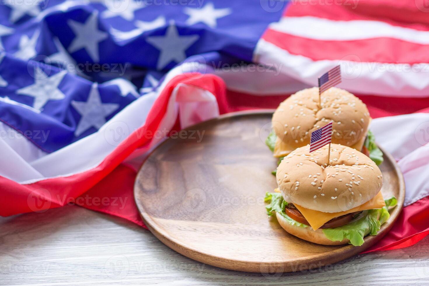 fechar-se do caseiro dois Hamburger com alface e queijo tem a americano bandeira PIN em a Hamburger colocada em uma de madeira cortar borda com a americano bandeira fundo em uma de madeira mesa foto