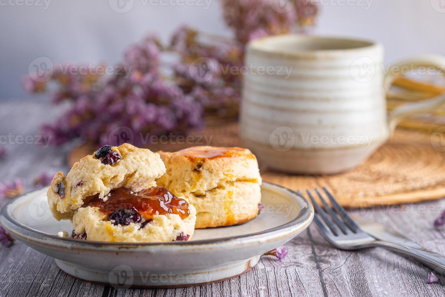 fechar-se do tradicional britânico scones em uma prato com uma chá copo e flor borrado fundo. espaço para texto foto