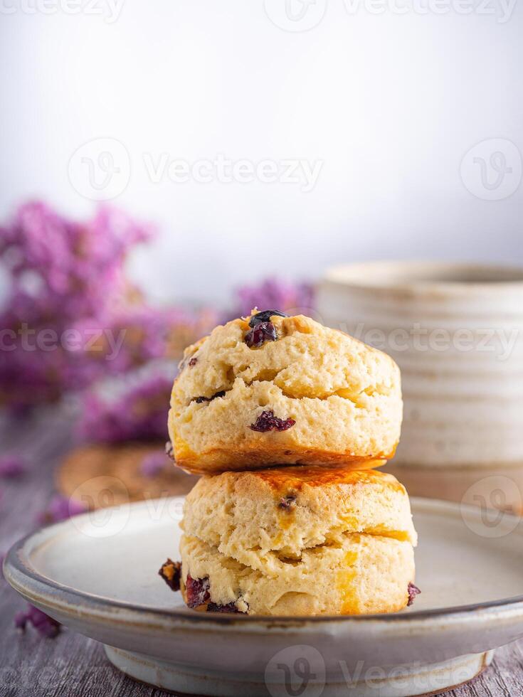 lado Visão do tradicional britânico scones em uma prato com uma xícara de chá e flor borrado fundo. espaço para texto foto