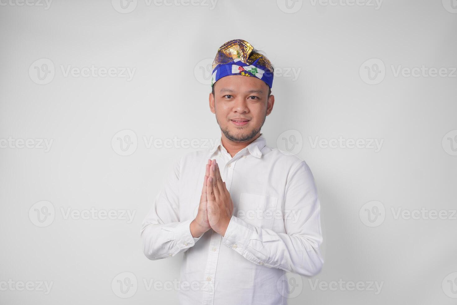 sorridente jovem balinesa homem vestindo tradicional cocar chamado udeng fazendo cumprimento ou bem-vinda gesto, isolado sobre branco fundo foto