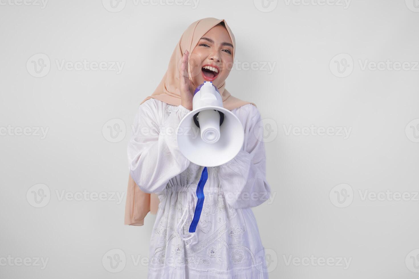 muito feliz ásia mulher vestindo hijab e branco vestir gritando para a megafone fazer anúncio, em pé sobre isolado branco fundo foto