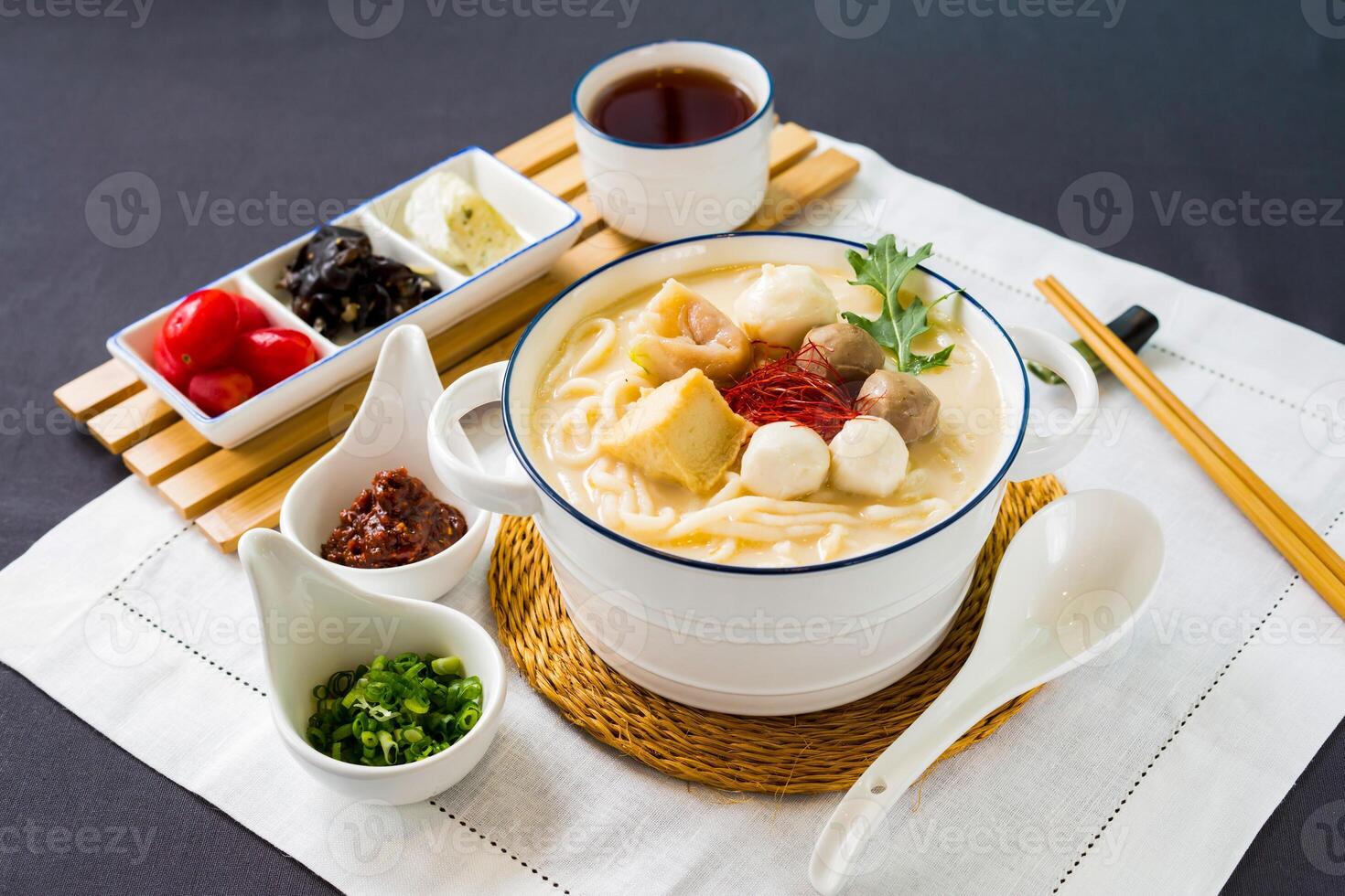 peixe udon dentro Grosso peixe sopa com aborrecimento cebola, Pimenta molho e pauzinhos servido dentro tigela isolado em guardanapo lado Visão do japonês Comida em mesa foto