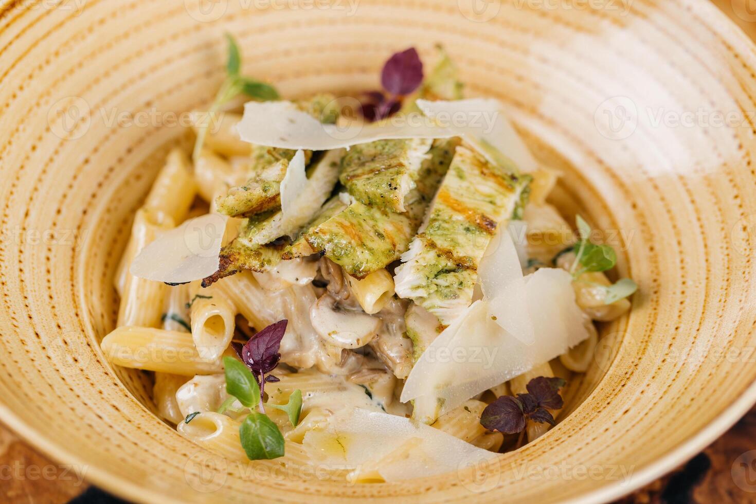 Macarrão Penne Panna e funghi massa com frango servido dentro prato isolado em mesa lado Visão do italiano comida rápida foto