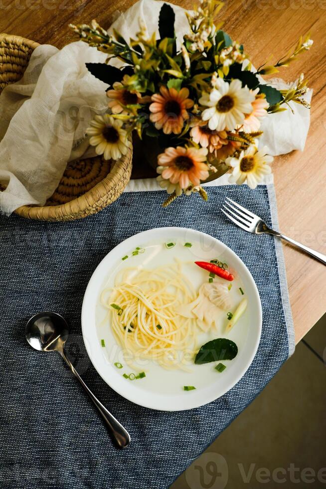 Claro limão frango Wonton incluir Macarrão, Primavera cebola e vermelho Pimenta servido dentro tigela isolado em guardanapo topo Visão do chinês sopa foto