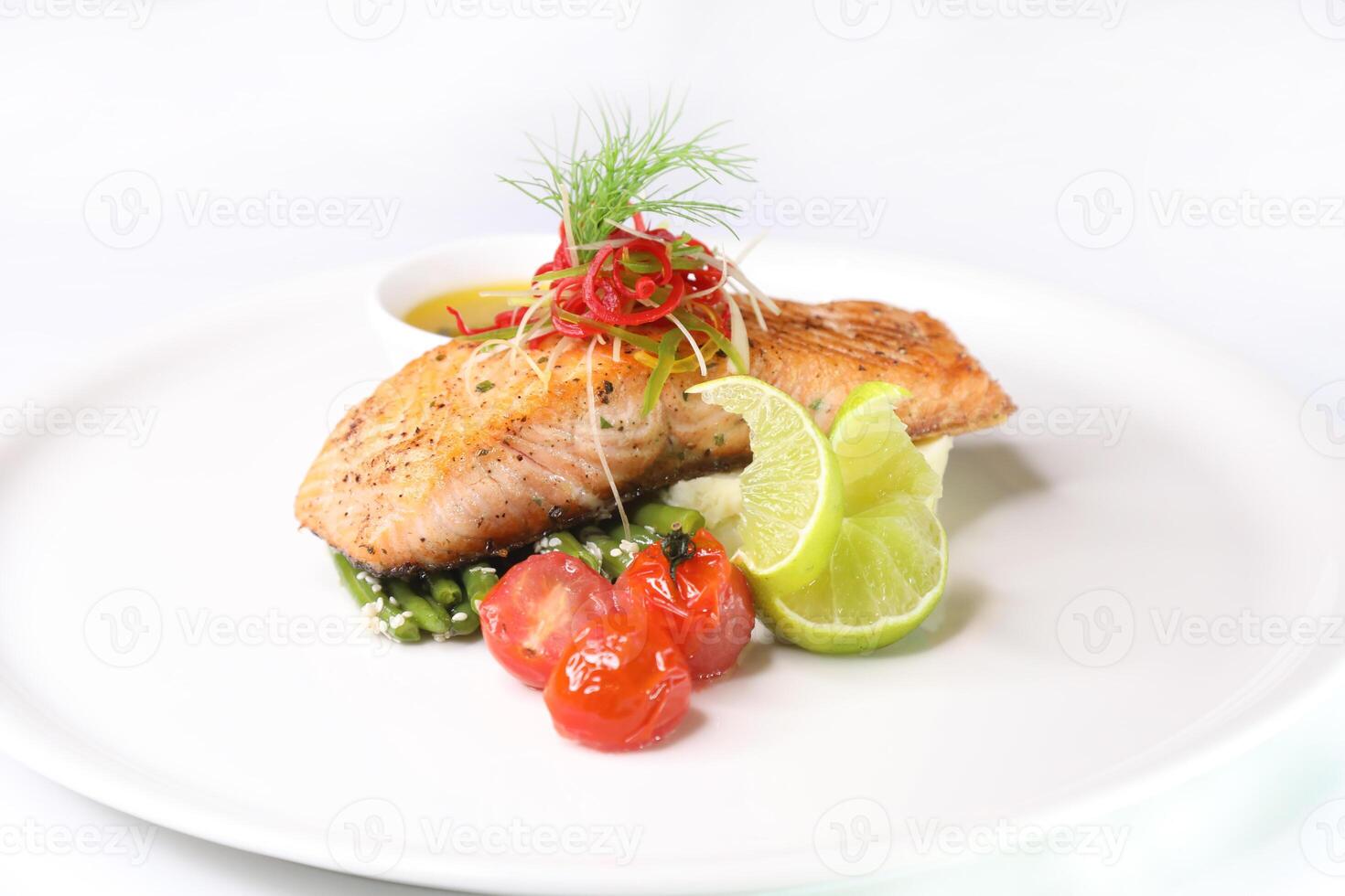 forno cozido salmão com limão, tomate e molho servido dentro prato isolado em fundo lado Visão do árabe Comida foto