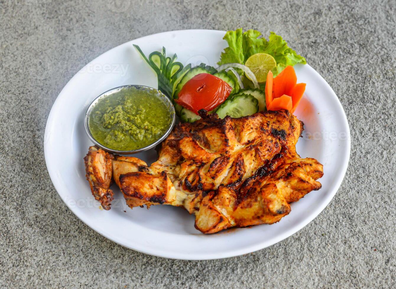 grelhado frango seio tikka peça com molho picante e salada servido dentro prato isolado em cinzento fundo lado Visão do indiano especiarias e paquistanês Comida foto