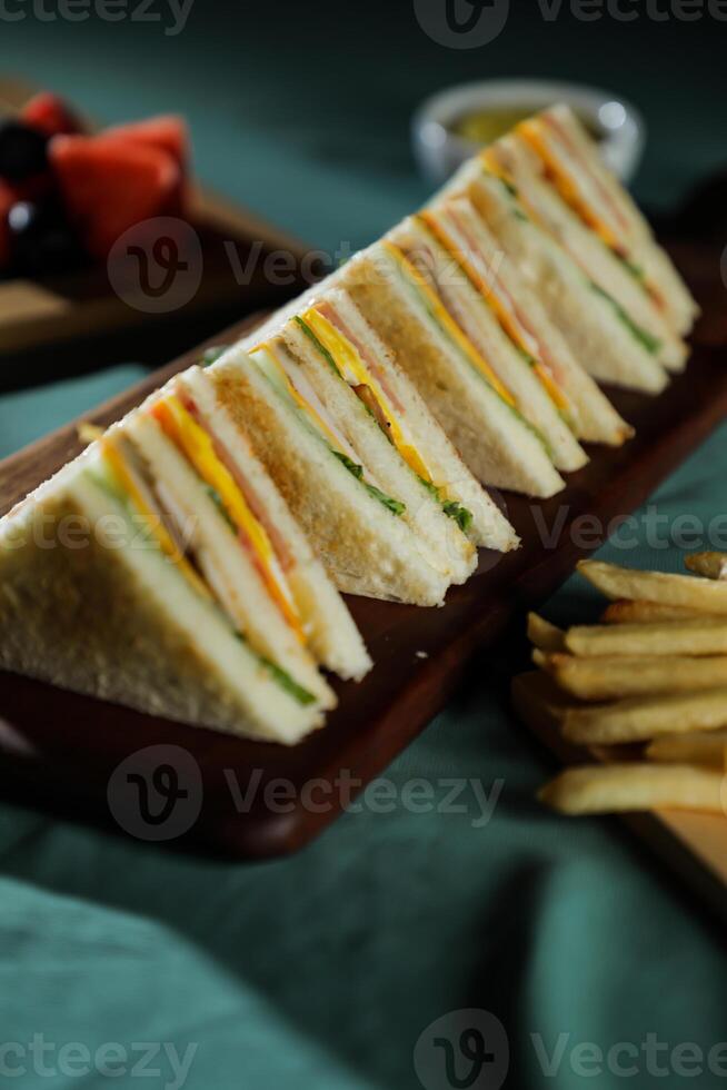 sortido clube sanduíche isolado em de madeira com maionese mergulho e francês fritas balde borda lado Visão do italiano velozes Comida em fundo foto