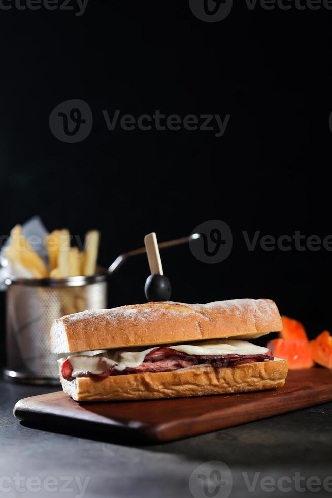 assado carne sub sanduíche com francês fritas balde servido em de madeira borda isolado em Sombrio fundo lado Visão do café da manhã Comida foto