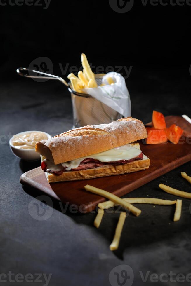 assado carne sub sanduíche com francês fritas balde servido em de madeira borda isolado em Sombrio fundo lado Visão do café da manhã Comida foto